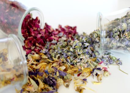 Dried flowers spilling out of glass container on table