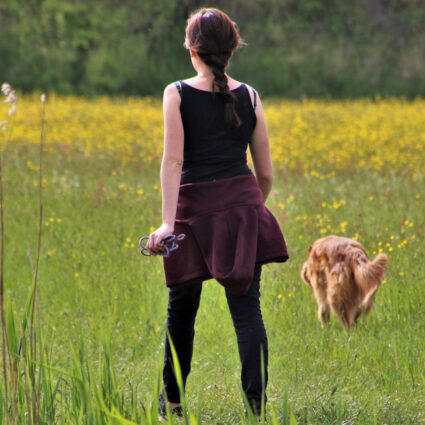 Girls and dog walking through sunlite neadow