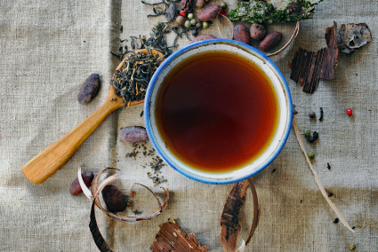 Picture of herbs on a table along with a cup of herbal tea